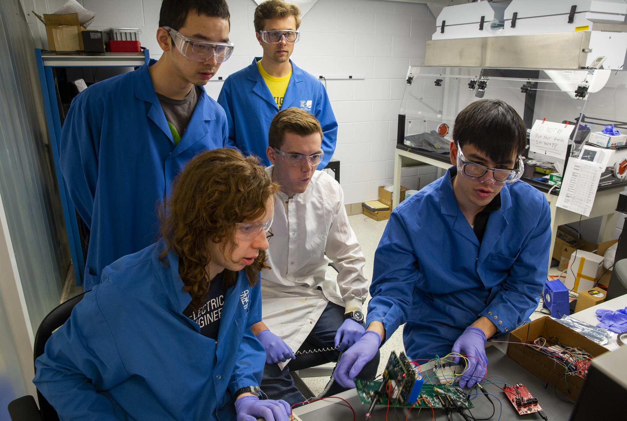Five MiTee team members working on a cluster of wires.