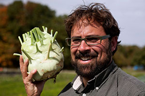 Jeremy Moghtader holding a plant next to his head
